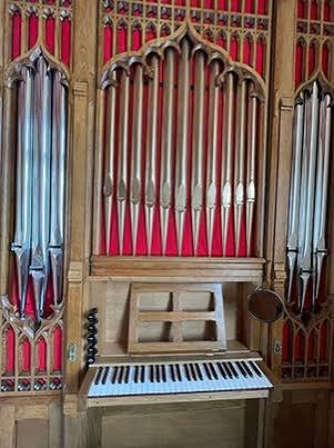 Organ case with red backing, silver pipes and console